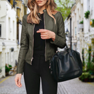 Frau in schwarzer Lederjacke und schwarzer Hose mit Ledertasche auf einer malerischen Straße. Modetrend, Damenmode, Streetstyle.