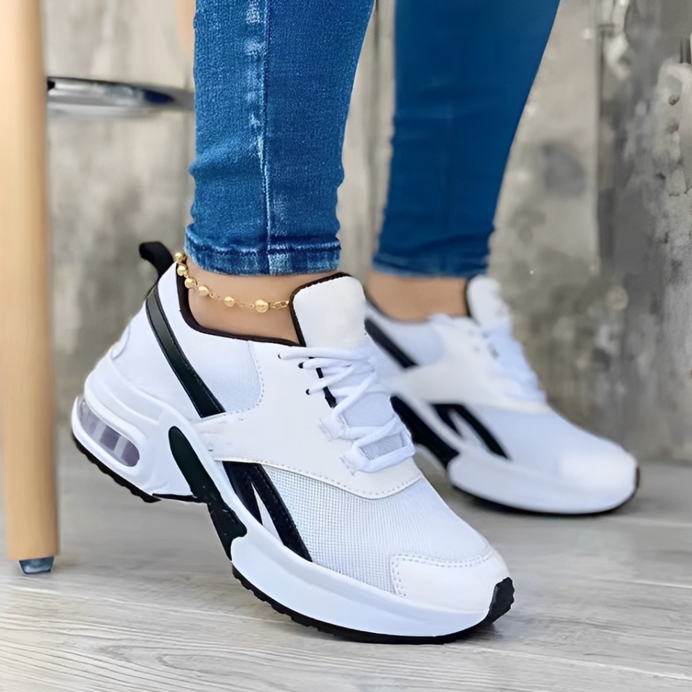 Weiße Sneaker mit schwarzem Streifen, Damenmode, sportlich, bequem, ideal für Freizeit und Fitness, kombiniert mit blauer Jeans.