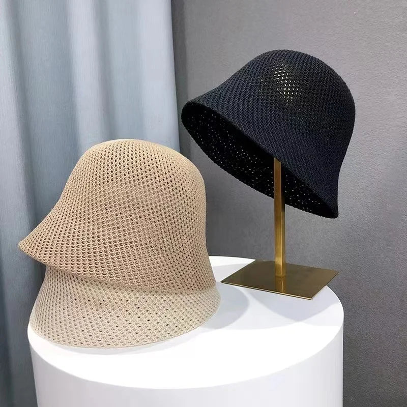 Zwei gehäkelte Sommer-Bucket-Hüte, beige und schwarz, auf einem Tisch. Atmungsaktiv, faltbar, ideal für Strand und Outdoor. Damenmode-Accessoire.