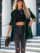 Frau in grünem Samtblazer, schwarzem Crop-Top und zerrissenen Jeans. Modetrend, Streetstyle, lässig, elegant, Damenmode, Accessoires.