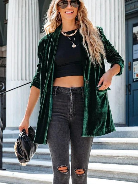 Frau in grünem Samtblazer, schwarzem Crop-Top und zerrissenen Jeans. Modetrend, Streetstyle, lässig, elegant, Damenmode, Accessoires.