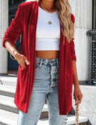 Frau in rotem Blazer, weißem Crop-Top und Jeans. Modetrend, Streetstyle, Damenmode, lässig, stilvoll, urbaner Look, Modeaccessoires.