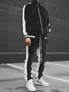 Schwarzer Trainingsanzug mit weißen Streifen, Herrenmode, sportlich, urbaner Stil, Straße.