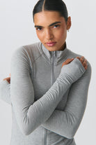 Frau in grauem Sportjacke mit Reißverschluss, ideal für Fitness und Outdoor-Aktivitäten. Bequem, atmungsaktiv, modisch. Perfekt für aktive Frauen.