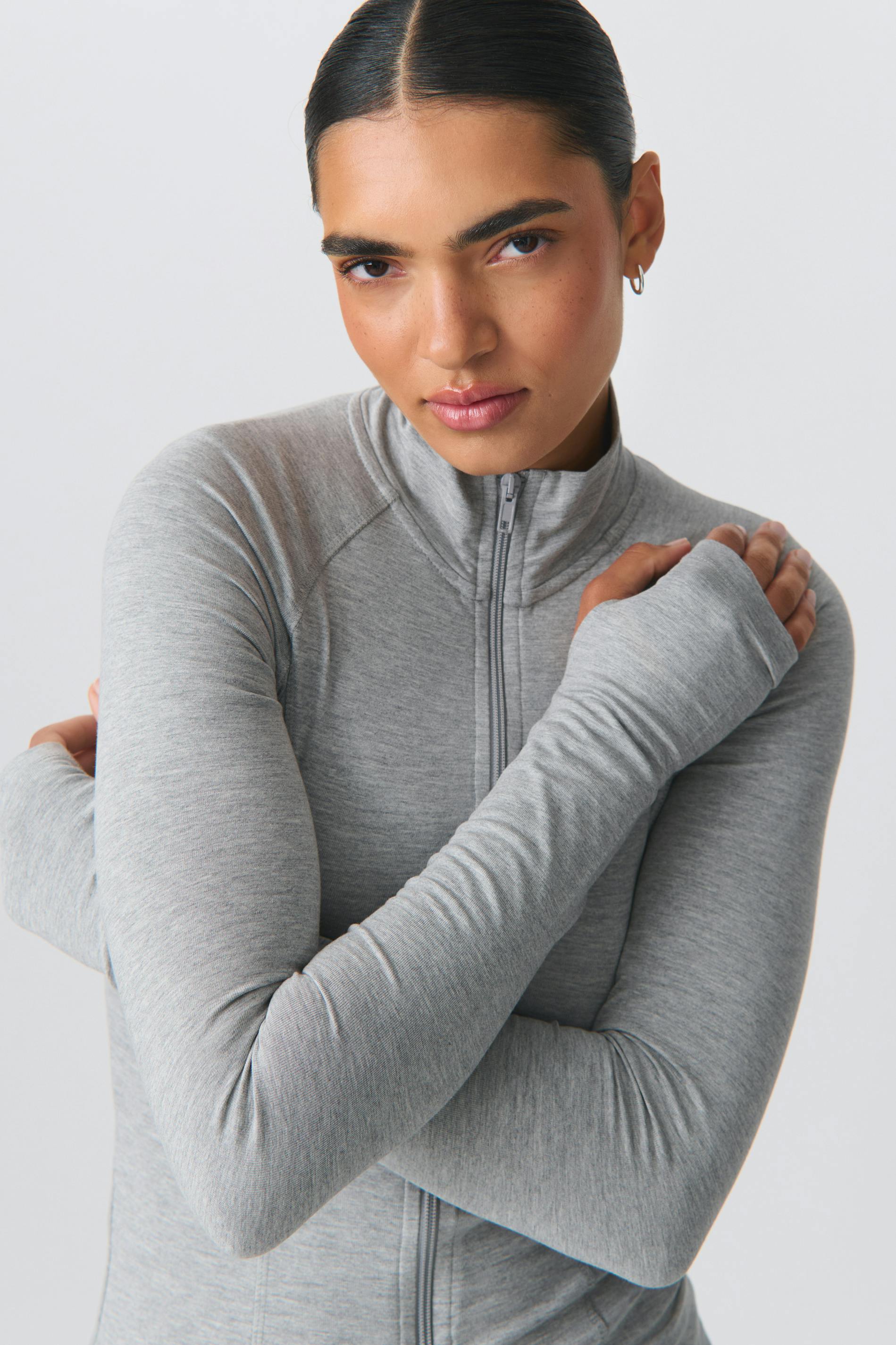 Frau in grauem Sportjacke mit Reißverschluss, ideal für Fitness und Outdoor-Aktivitäten. Bequem, atmungsaktiv, modisch. Perfekt für aktive Frauen.