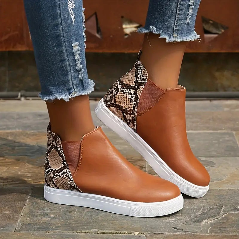 Damen-Sneaker in Braun mit Schlangenmuster, knöchelhoch, kombiniert mit zerrissenen Jeans. Modische Freizeitschuhe, ideal für den Herbst.