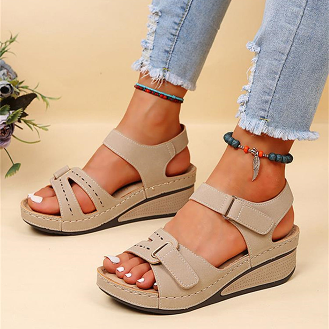 Beige Sandalen mit Keilabsatz, Klettverschluss und offener Zehenpartie, kombiniert mit zerrissenen Jeans. Perfekt für Sommermode und Komfort.