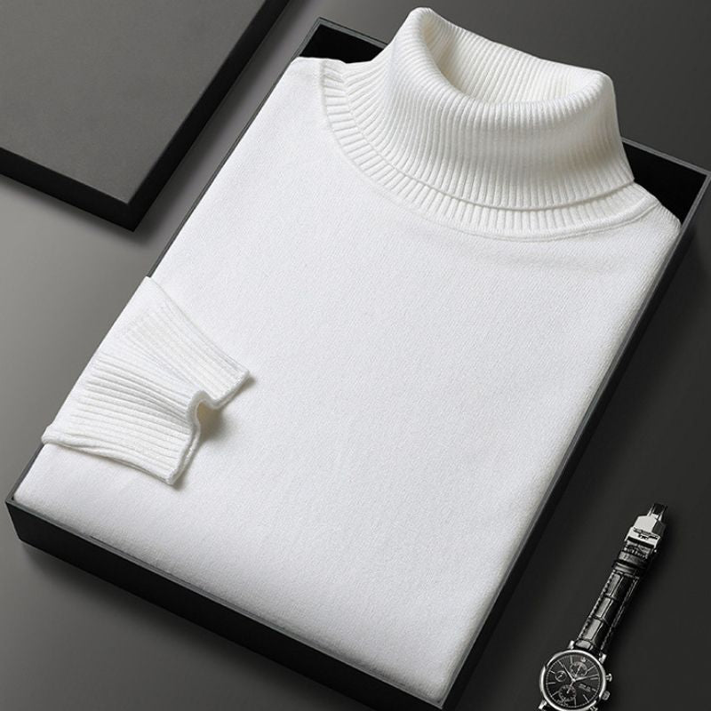 Weißer Rollkragenpullover aus Baumwolle, elegant gefaltet in schwarzer Box. Perfekt für stilvolle Wintermode und zeitlosen Komfort.