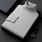 Grauer Rollkragenpullover aus Kaschmir, elegant gefaltet in schwarzer Geschenkbox, ideal für stilvolle Herrenmode. Luxuriös, weich, zeitlos.
