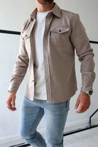 Herrenmode: Beige Hemdjacke aus Baumwolle, kombiniert mit weißem T-Shirt und blauen Jeans. Stilvoll, lässig, ideal für den modernen Look.