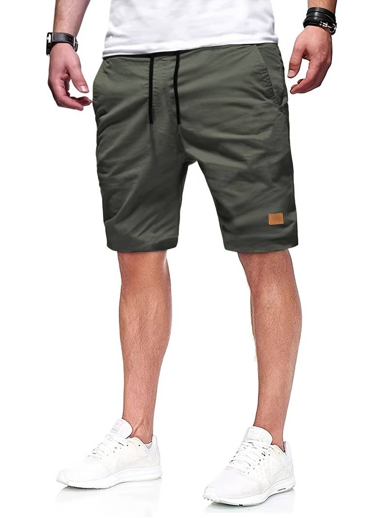 Mann trägt olivgrüne Shorts, weißes T-Shirt und weiße Sneaker, lässiger Sommerlook.