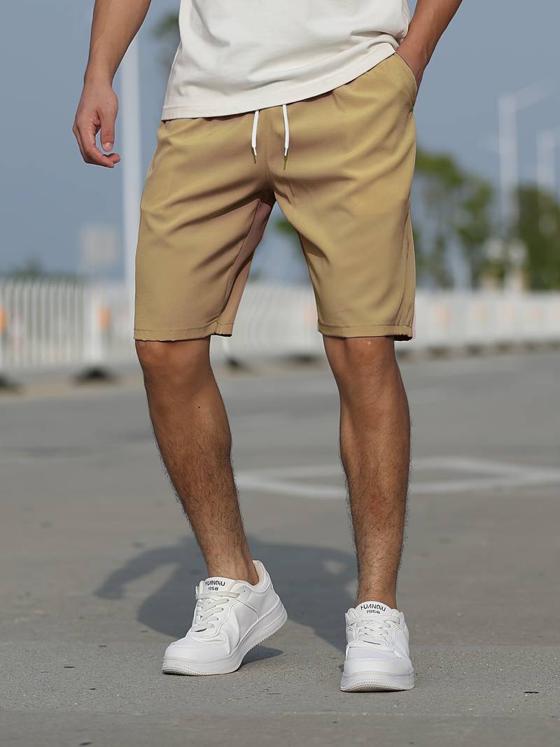 Mann in beige Shorts und weißen Sneakers auf Straße, lässige Sommermode, Herrenbekleidung.