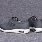 Graue orthopädische Schuhe mit Klettverschluss, atmungsaktivem Material und rutschfester Sohle. Ideal für Komfort und Fußgesundheit.