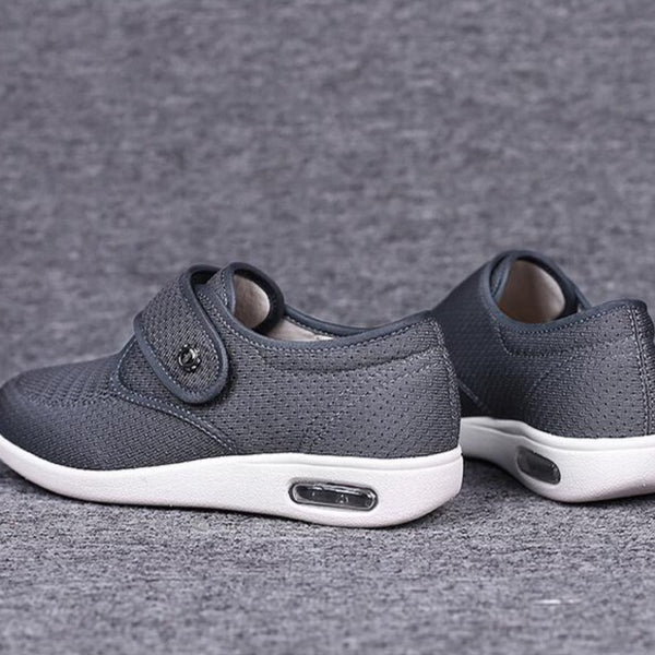Graue orthopädische Schuhe mit Klettverschluss, atmungsaktivem Material und rutschfester Sohle. Ideal für Komfort und Fußgesundheit.