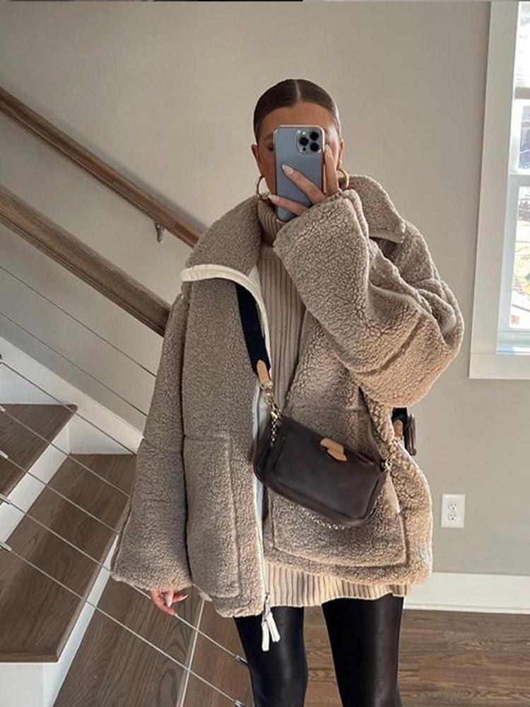 Frau in übergroßer Teddyjacke, Lederleggings und Handtasche, macht Selfie. Trendige Wintermode, gemütlicher Look, Streetstyle.