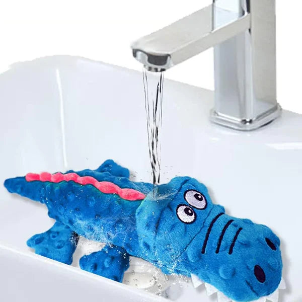 Blaues Krokodil-Plüschtier im Waschbecken unter fließendem Wasser. Perfektes Spielzeug für Kinder, waschbar, weiches Material, langlebig.