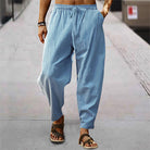 Mann in blauer Leinenhose und Sandalen auf Gehweg, lässige Sommermode.