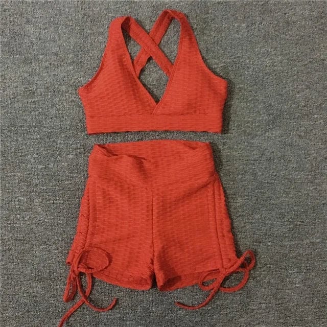 Rotes Sportset mit kurzen Shorts und überkreuztem Top, ideal für Fitness und Yoga. Atmungsaktives Material, modisch und bequem.