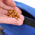 Hand hält Katzenfutter vor blauem Stoffbeutel. Hochwertiges Trockenfutter, ideal für Katzen. Perfekt für unterwegs, praktisch und nährstoffreich.