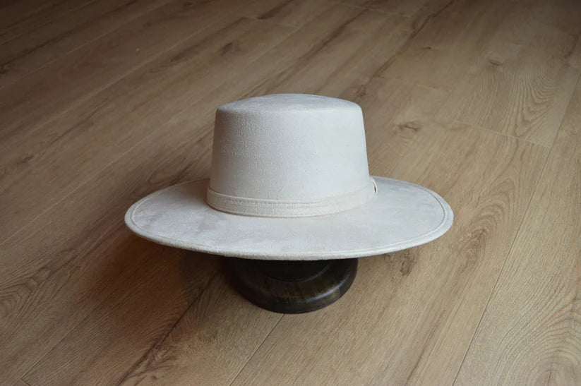 Breiter cremefarbener Filzhut auf Holzboden, stilvoll und zeitlos. Perfekt für Mode, Accessoires, Cowboyhut, Westernstil, Unisex.