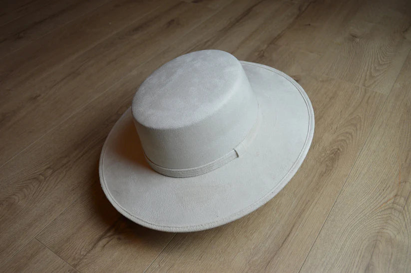 Eleganter weißer Filzhut mit breiter Krempe auf Holzboden, ideal für stilvolle Outfits. Perfekt für Modebegeisterte und Hutliebhaber.