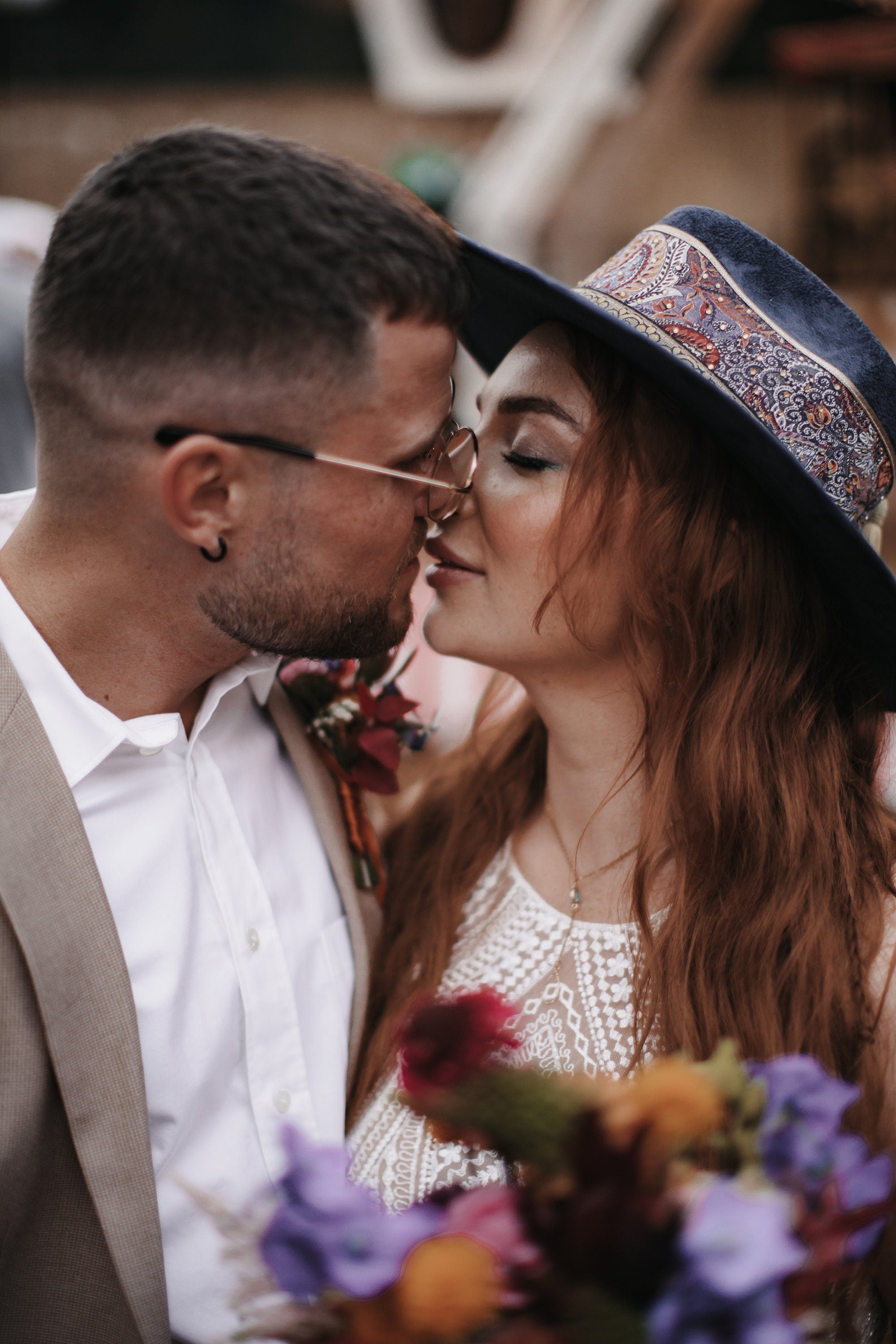 Paar in romantischer Umarmung, Mann im Anzug, Frau mit Hut und Blumenstrauß. Perfekt für Hochzeitsfotografie, Liebe, Romantik, Boho-Stil.