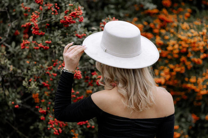 Frau mit weißem Hut vor herbstlichem Hintergrund aus roten und orangefarbenen Beeren. Modetrend, Herbstmode, stilvolle Accessoires.