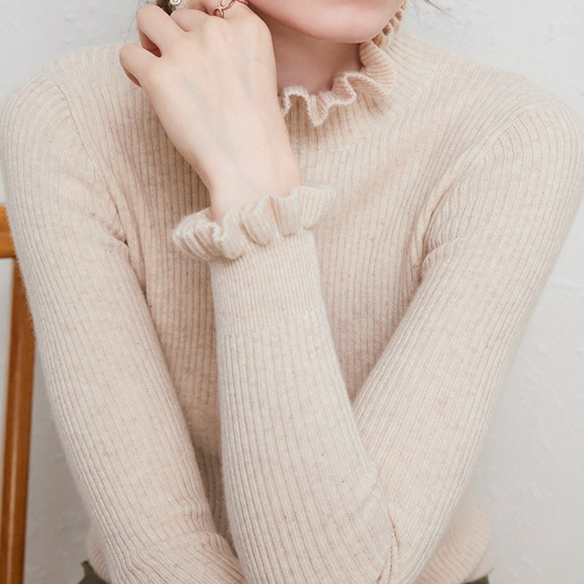 Damenpullover aus beigem Strick mit Rüschenkragen und -ärmeln, elegant und modisch, ideal für Herbstmode. Hochwertige Strickware.
