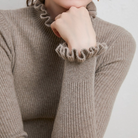 Damenpullover aus beigem Strick mit Rüschenkragen und -ärmeln, modisch und elegant. Perfekt für Herbstmode und stilvolle Outfits.