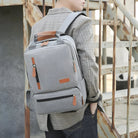 Grauer Rucksack aus Stoff mit Lederakzenten, ideal für Schule oder Reisen, modisches Design.