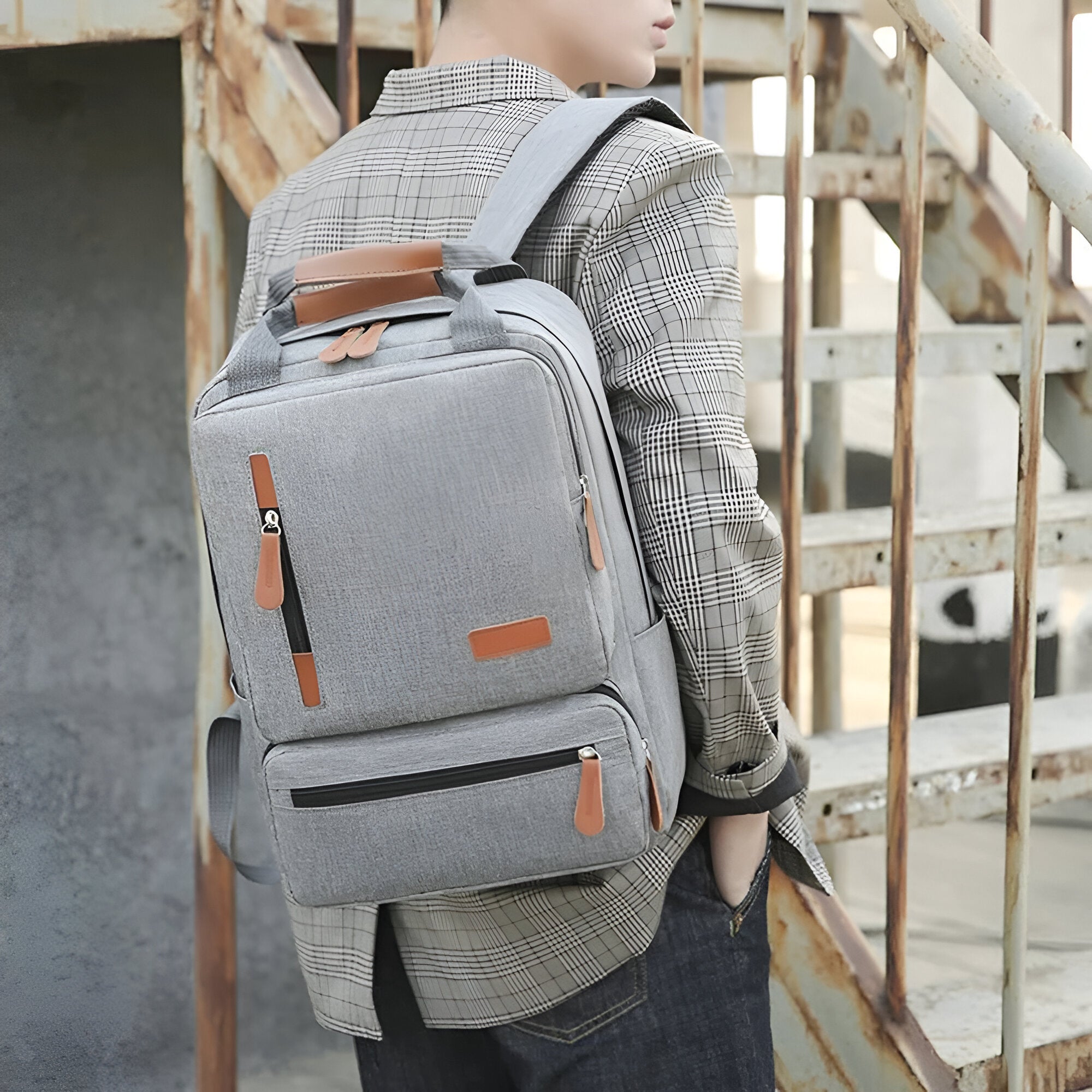 Grauer Rucksack aus Stoff mit Lederakzenten, ideal für Schule oder Reisen, modisches Design.