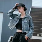 Damen-Jeansjacke mit Nieten und Graffiti-Design, kombiniert mit schwarzem Crop-Top und Kappe. Modische Streetwear für trendbewusste Frauen.