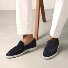 Elegante schwarze Herren-Slipper aus Wildleder, kombiniert mit weißen Hosen. Perfekt für stilvolle Freizeit- und Business-Looks.