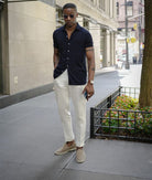 Elegante Herren-Loafer aus Wildleder, kombiniert mit weißer Hose und dunkelblauem Hemd. Perfekt für stilvolle, urbane Sommermode.