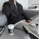 Schwarzer Strickpullover mit Reißverschluss, kombiniert mit grauer Hose und New Balance Sneakers. Perfekt für lässige Herrenmode im Herbst.