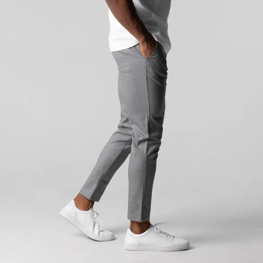 Mann trägt graue Chinohose, weiße Sneaker, lässiger Stil, Herrenmode, bequeme Passform.