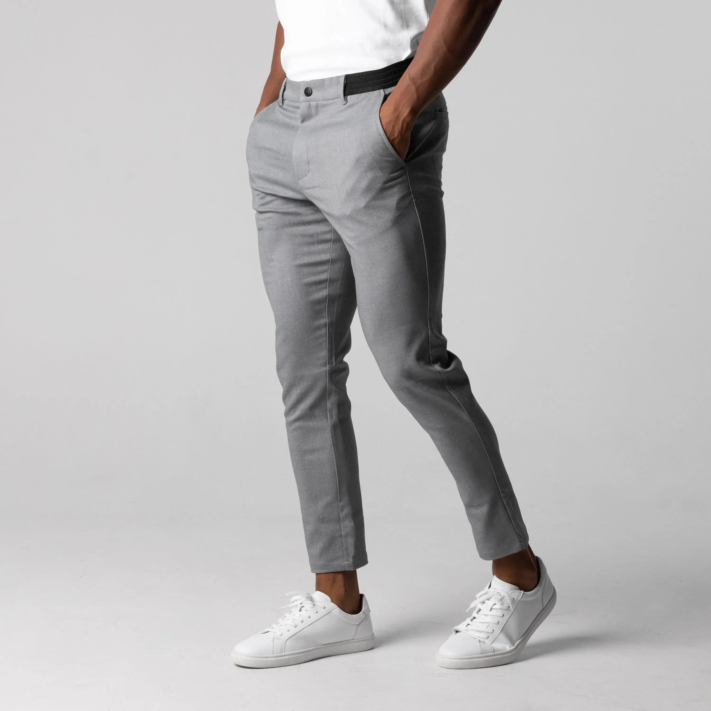 Graue Herren-Chinohose, schmal geschnitten, aus Baumwolle, kombiniert mit weißen Sneakers.