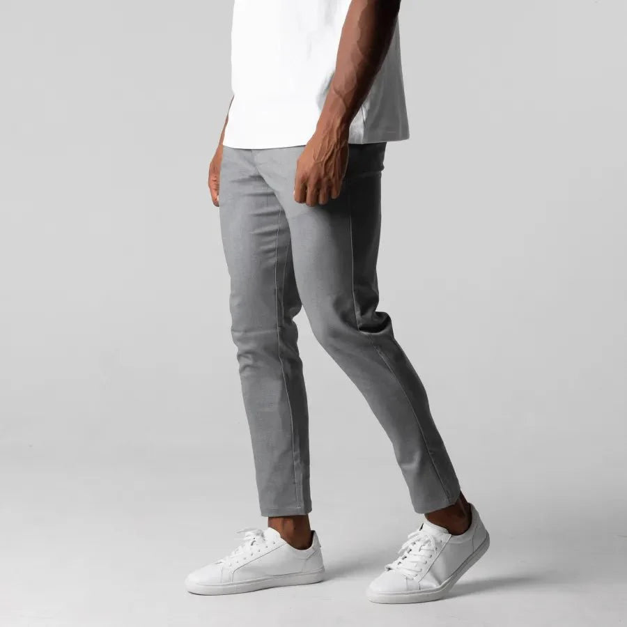 Graue Chinohose für Herren, schlank geschnitten, aus Baumwolle, kombiniert mit weißen Sneakers.