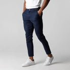 Mann trägt dunkelblaue Chinohose, weiße Sneaker, weißes T-Shirt, modisch, lässig.