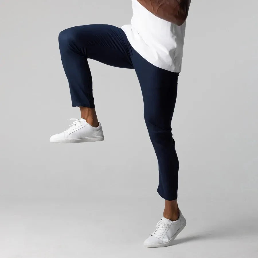 Mann trägt dunkelblaue Chinos, weiße Sneaker, weißes T-Shirt, sportlich, modisch, bequem.