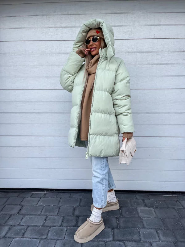 Damen Winterjacke in Pistaziengrün, gesteppt, mit Kapuze. Modischer Look mit Jeans und beigem Pullover. Perfekt für kalte Tage.
