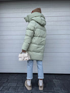 Damen Winterjacke in Pistaziengrün, gesteppt, mit Kapuze. Modischer Mantel, ideal für kalte Tage. Perfekt kombiniert mit Jeans und Beanie.