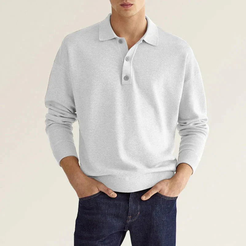 Graues Poloshirt für Herren, langärmlig, aus Baumwolle, klassischer Kragen, ideal für Freizeit und Büro, kombiniert mit dunklen Jeans.