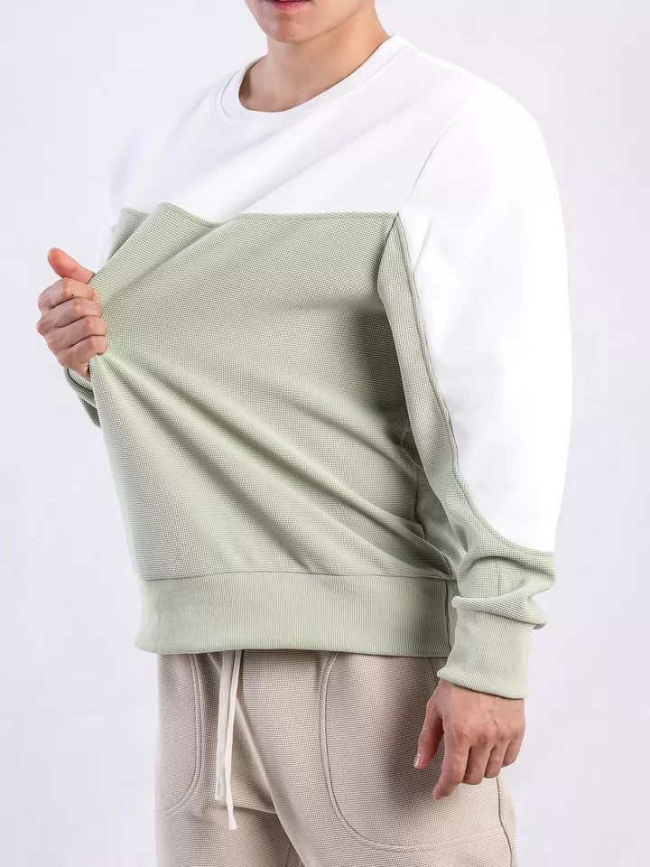 Mann trägt zweifarbiges Sweatshirt, weiß und grün, aus Baumwolle, lässiger Stil.