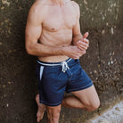 Marineblaue Herren-Badeshorts aus recyceltem Polyester mit weißen Nähten. Ideal für umweltbewusste Mode und nachhaltige Bademode.