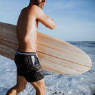 Marineblaue Herren-Badeshorts aus recyceltem Polyester mit orangefarbenen Details, ideal für Strand und Surfen. Nachhaltige Mode für Männer.