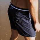 Marineblaue Herren-Badeshorts aus recyceltem Polyester mit orangefarbenen Details, ideal für nachhaltige Mode und Strandaktivitäten.