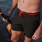 Khaki Badeshorts für Herren aus recyceltem Polyester mit roten Details, ideal für Strand und Pool. Nachhaltige Herrenmode, umweltfreundlich.