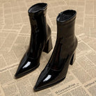 Schwarze Lackleder-Stiefeletten mit spitzem Absatz auf Zeitungshintergrund. Modische Damenstiefel, ideal für Herbst und Winter.