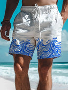 Weiße Badeshorts mit blauem Wellenmuster und Schriftzug "Go with the flow" am Strand.